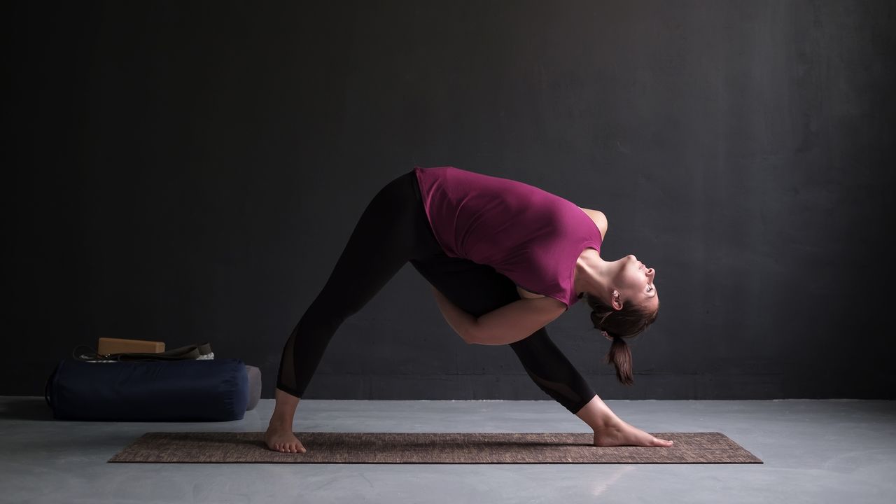 Check out the best yoga mats of 2021. Shown here, a woman standing in Utthita Trikonasana, extended triangle pose, on a yoga mat.