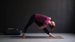 Check out the best yoga mats of 2022. Shown here, a woman standing in Utthita Trikonasana, extended triangle pose, on a yoga mat.