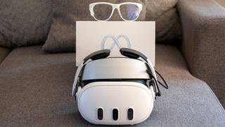 A Meta Quest 3 headset with its box and a pair of smart glasses behind it