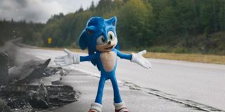 Sonic stands in front of a pile of smoking debris on a long country road in a scene from the film So