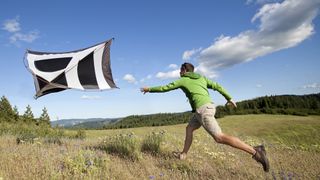 A man chasing his tent as it blows away in the wind