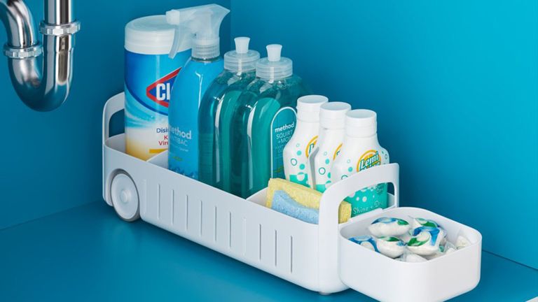 YouCopia white under sink organizer caddy with wheels containing an assortment of cleaning products and dishwasher tablets