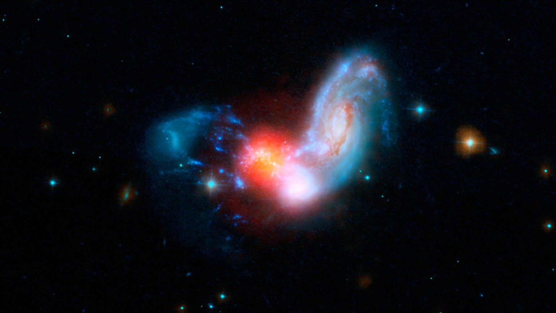 Dos galaxias espirales chocan, provocando un estallido de formación estelar (rojo).  Los astrónomos sospechan que la Vía Láctea alcanzó su tamaño actual a través de una serie de fusiones como esta.