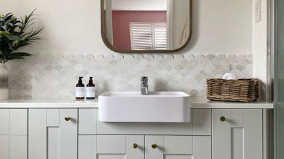 neutral en suite bathroom with fish scale tiles and vanity unit and cupboards