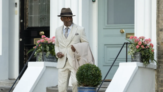 Barrington (Lennie James), dressed in a smart cream suit and hat, trots down a flight of steps outside a house in Mr Loverman