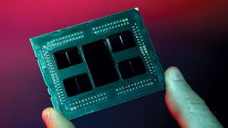 A close up image of an AMD Epyc processor being held by an unseen person in front of a red screen