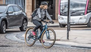 A female cyclist riding a Ribble e-bike on a city street