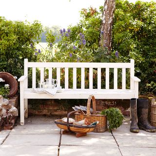 farmhouse exterior with terrace has white painted garden bench basket and trug