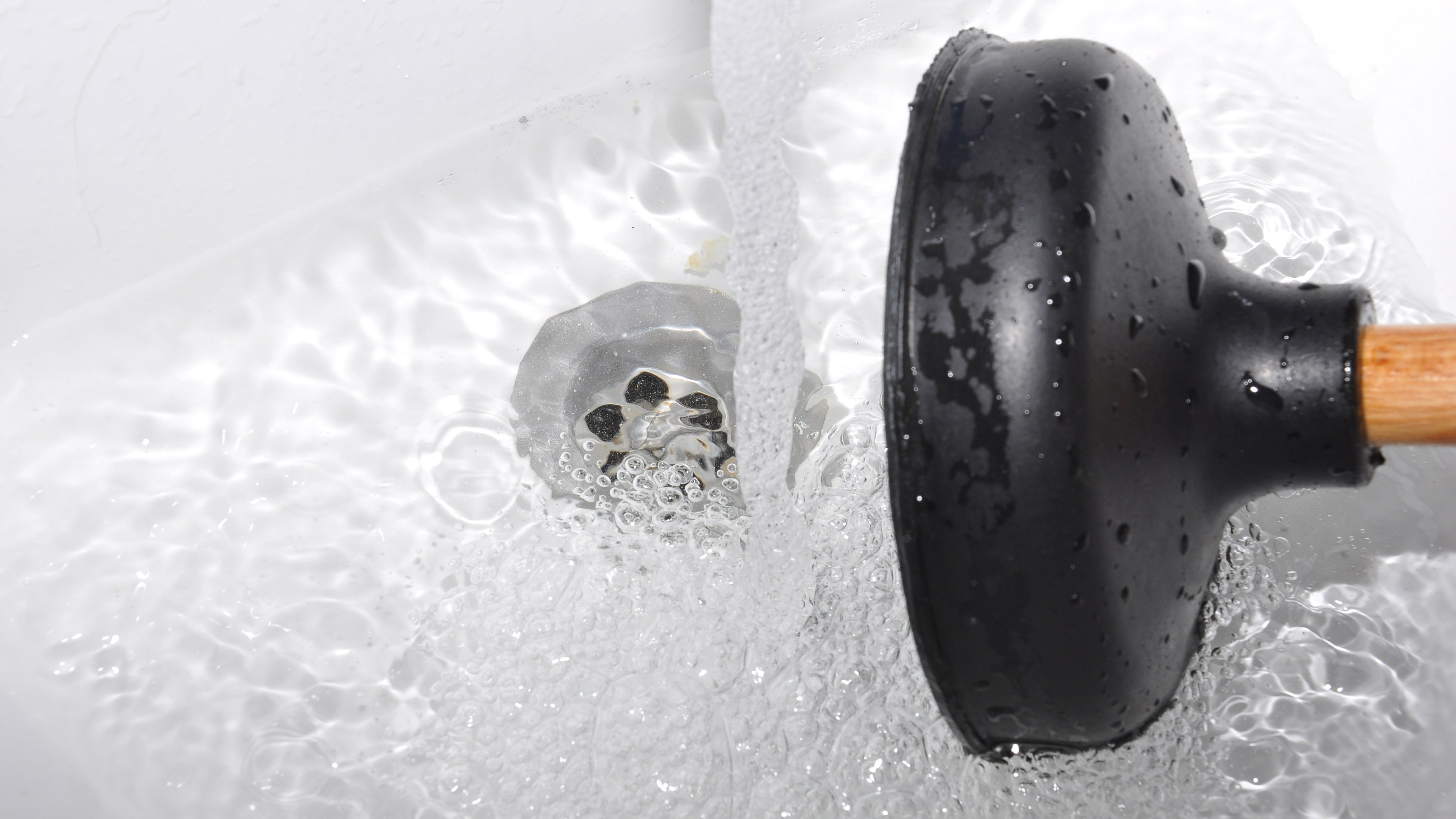 A plunger next to a shower drain