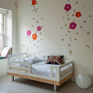 kids room with printed white wall and white kids bed