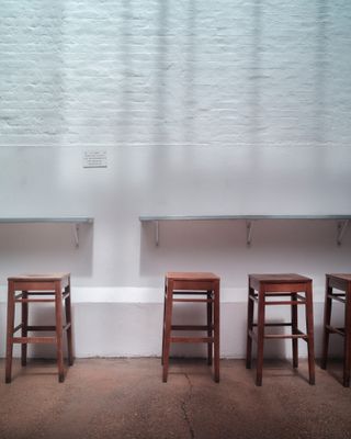 Four wood stools at the side of a room.