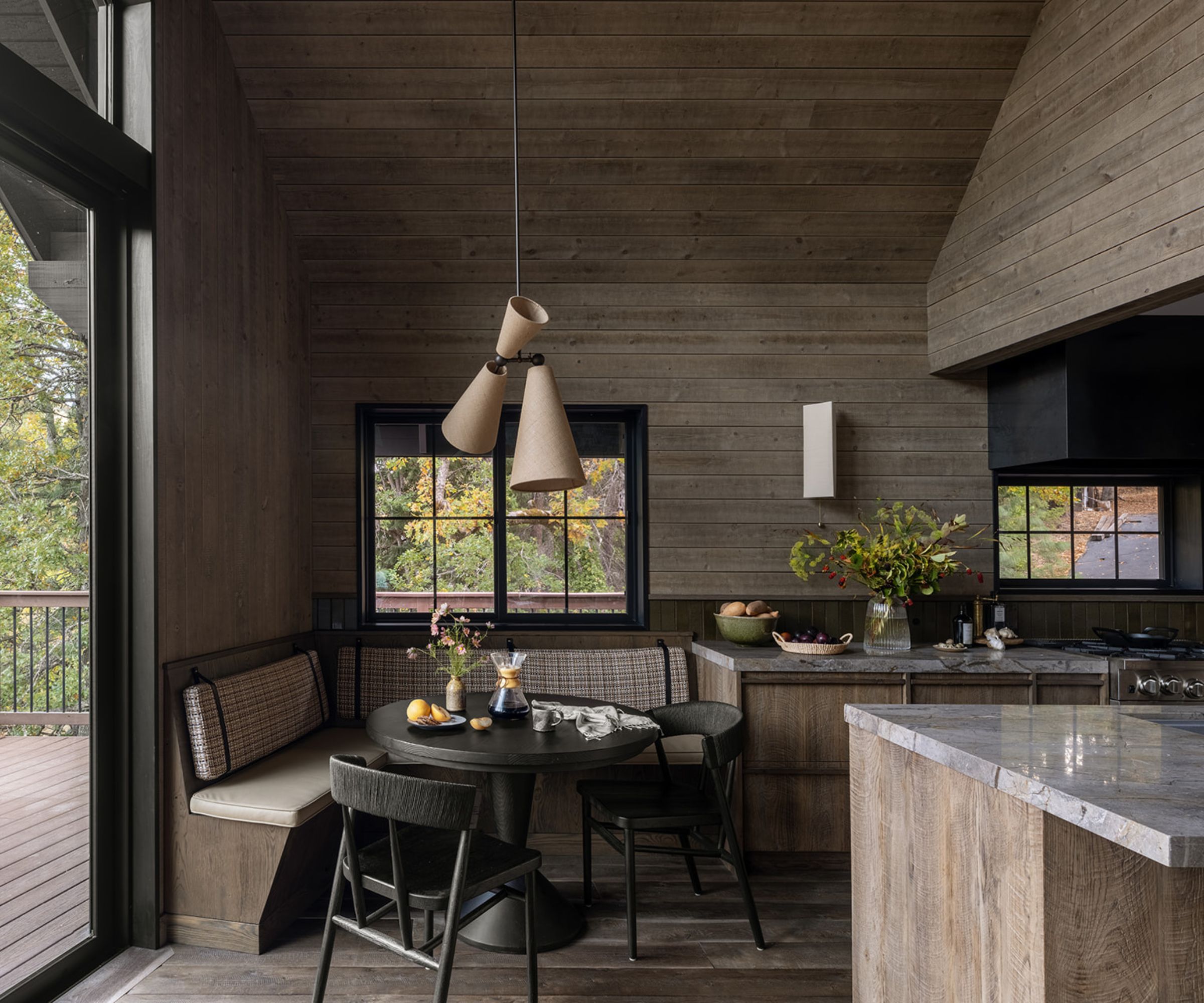 A Cabin kitchen with a custom banquette seating area created using the same wood as the kitchen cabinets and upholstered in patterned fabric