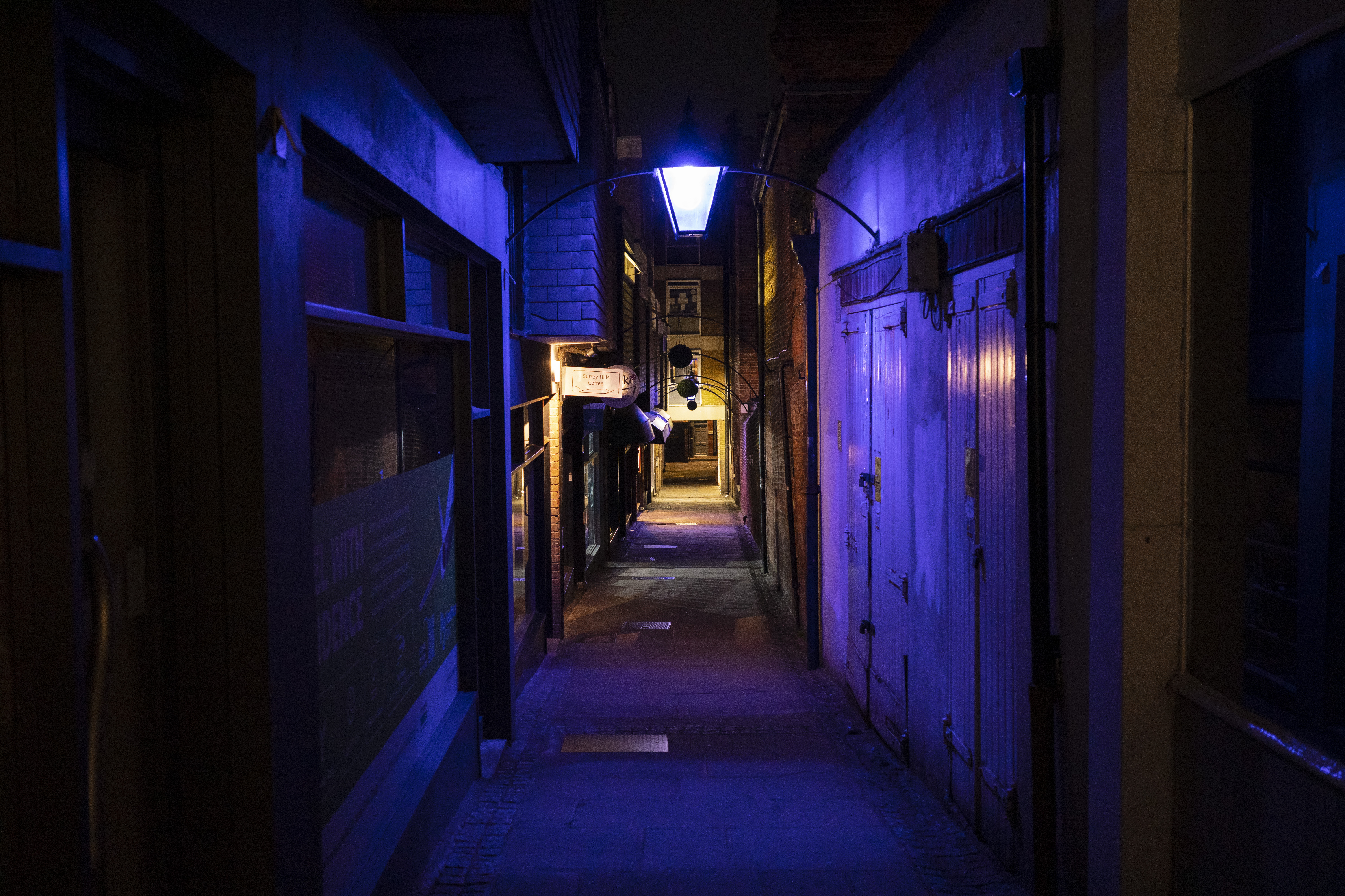 A narrow alleyway lit up by artificial purple lights