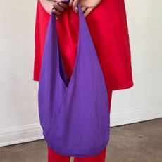 A photo of a woman wearing a red dress and carrying a purple bag.