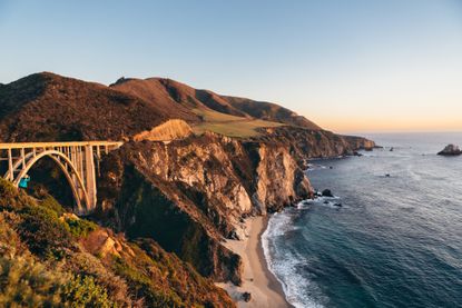 The Bixby Creek Bridge, Pacific Coast Highway 1 and greater Californian Big Sur coastline with a dramatic sunset.