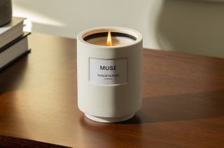 A lit candle in a white ceramic jar