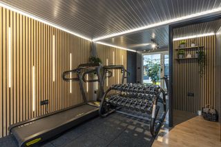 home gym with a treadmill, weights and panelled walls