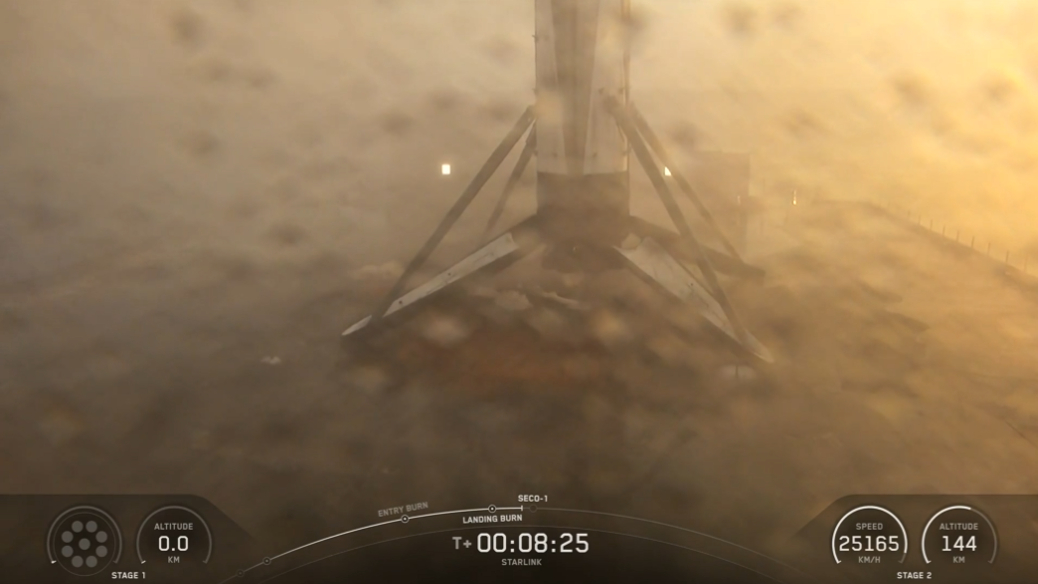 a water spattered lens shows a hazy platform with a 4-legged fuselage standing upright.