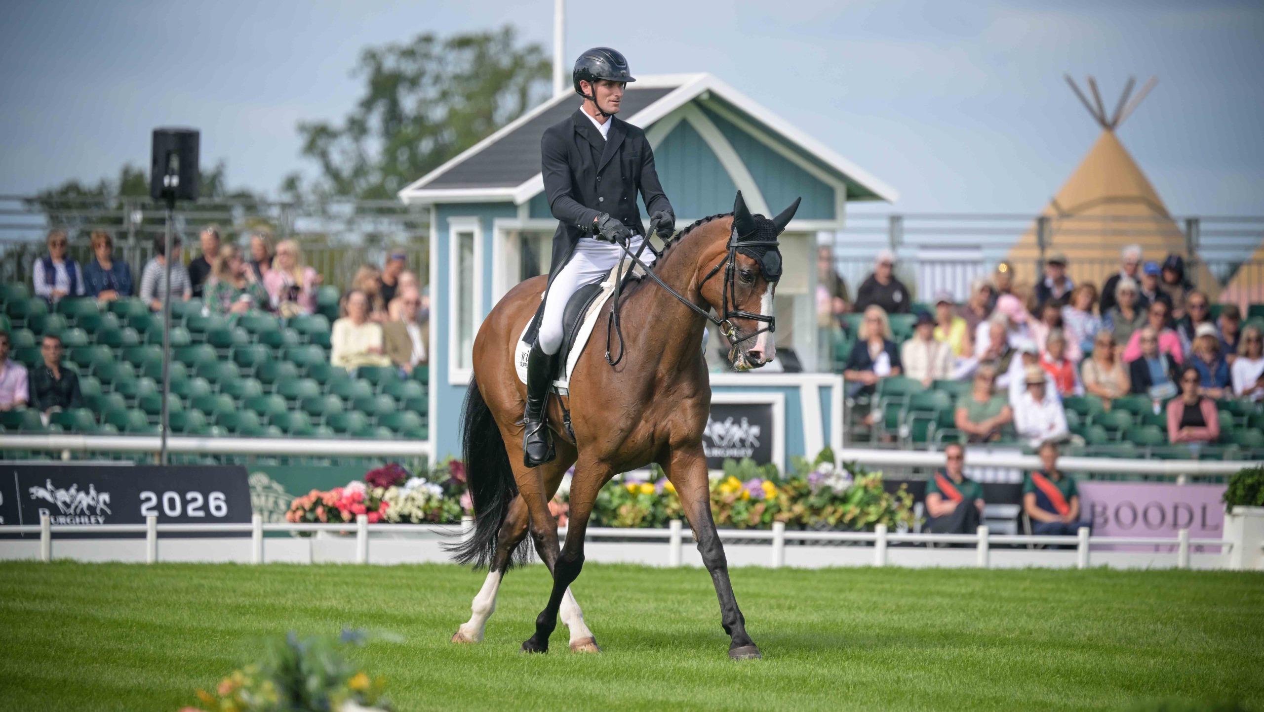 Jack Pinkney in a black tailcoat riding a half pass on his horse, Claragh Olala, during their dressage test at the 2026 Defender Burghley Horse Trials