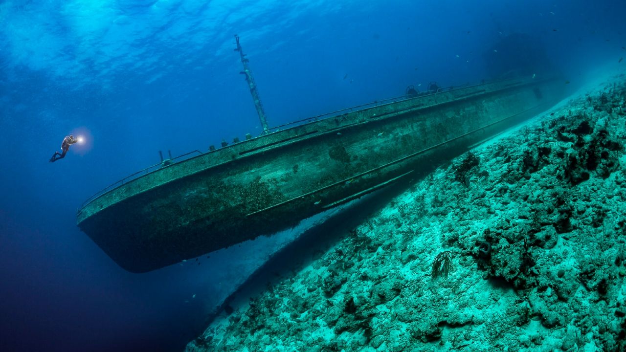 A scuba diver swimming near a shipwreck on the seafloor
