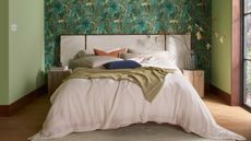 a bedroom with wallpaper and green painted wallls