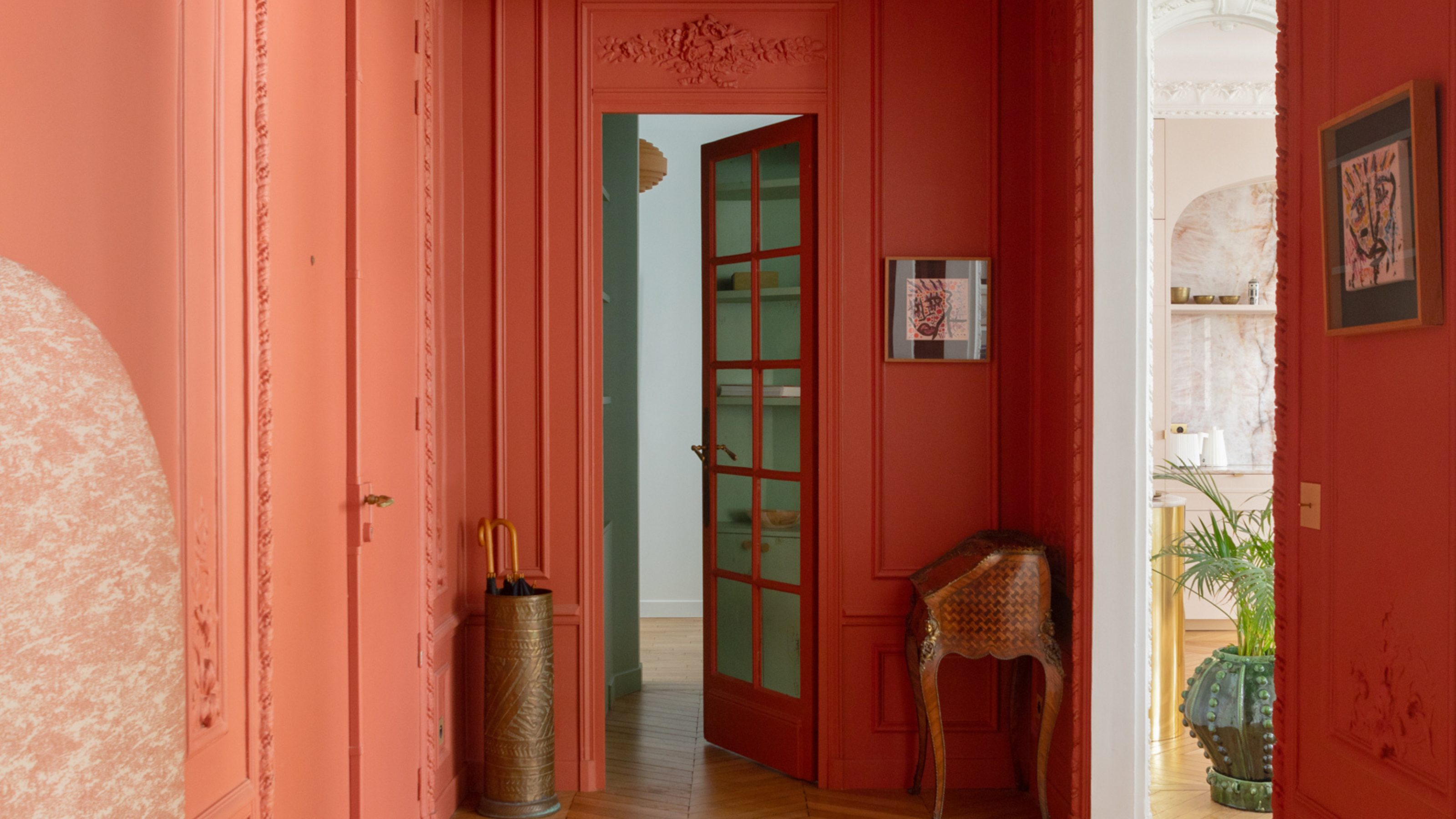 coral orange color drenched hallway in Paris with crown molding