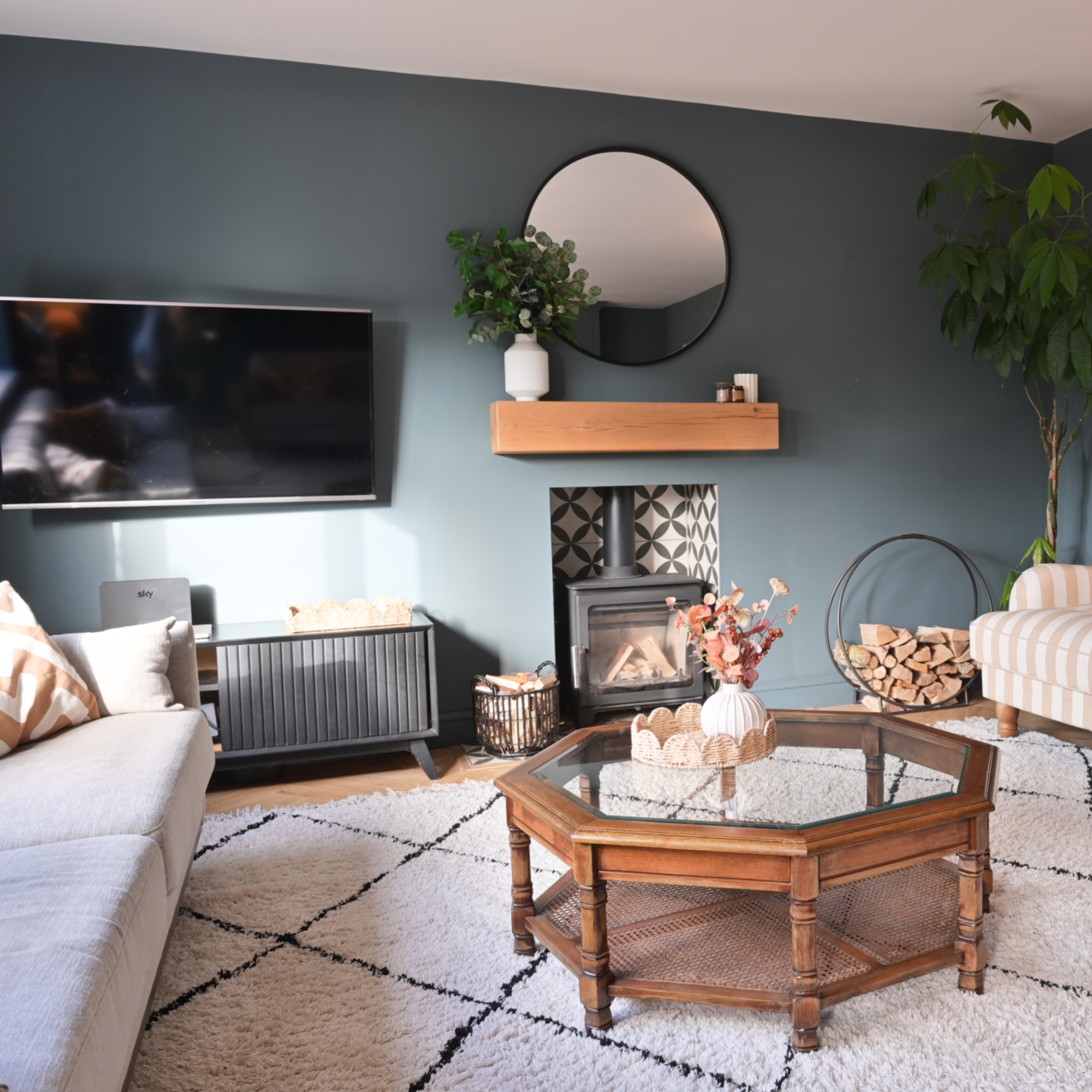 blue living room with hexagonal coffee table, rug, log burner, tv, beige sofa
