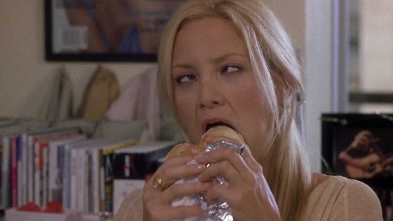 Kate Hudson biting into a burger with her eyes crossed in How To Lose A Guy In 10 Days