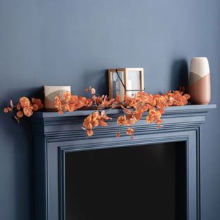 Dunelm orange garland on fireplace with grey wall