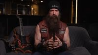 Zakk Wylde on a couch next to one of his guitars