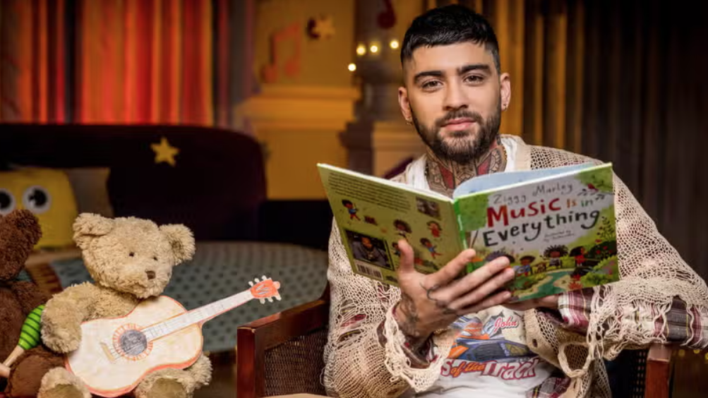 Former One Direction star Zayn Malik sits next to a teddy bear holding a toy guitar to read a &quot;Bedtime Story&quot; on CBeebies