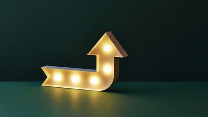 A lighted yellow arrow points up against a dark green background.