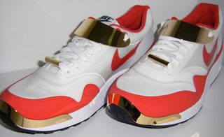 Pair of Nike Air Max sneakers, in red and white, with gold adornments, white background