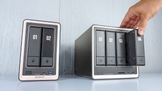 A person inserting a hard drive into one of the drive bays on the Ugreen DXP4800 GT