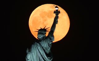 The Flower Moon, as seen behind the Statue of Liberty in Jersey City, NJ in the U.S. on May 7, 2020.