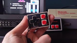 Hand holding IINE Gamebrick Mini controller with NES in backdrop next to Sony Trinitron PVM CRT and Mega Man 2 intro on screen.