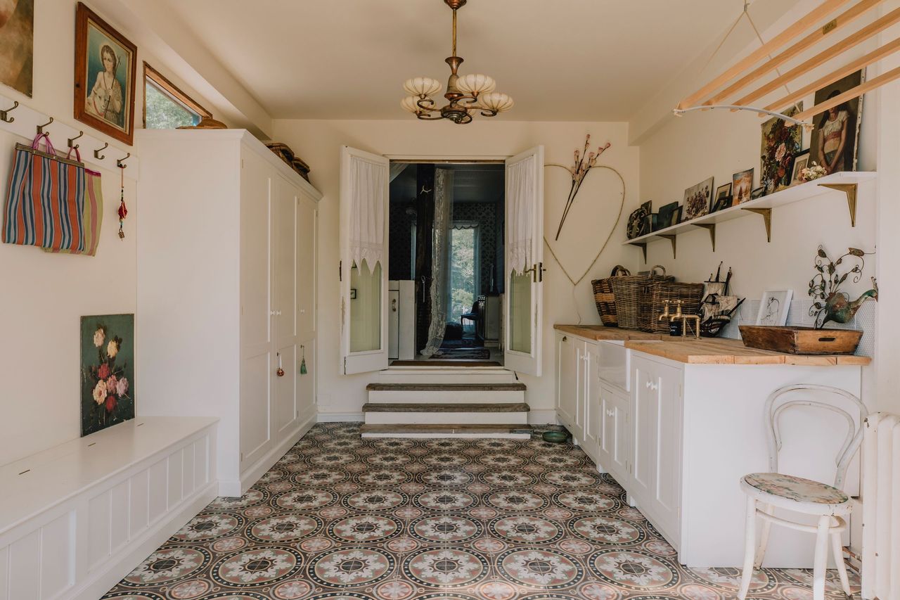 A boot room with sink and pink cupboards leads into the main hall of the house