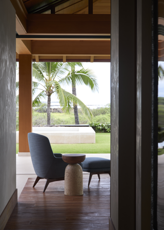 An outdoor living space with a blue sofa chair and pouf, and a structural side table