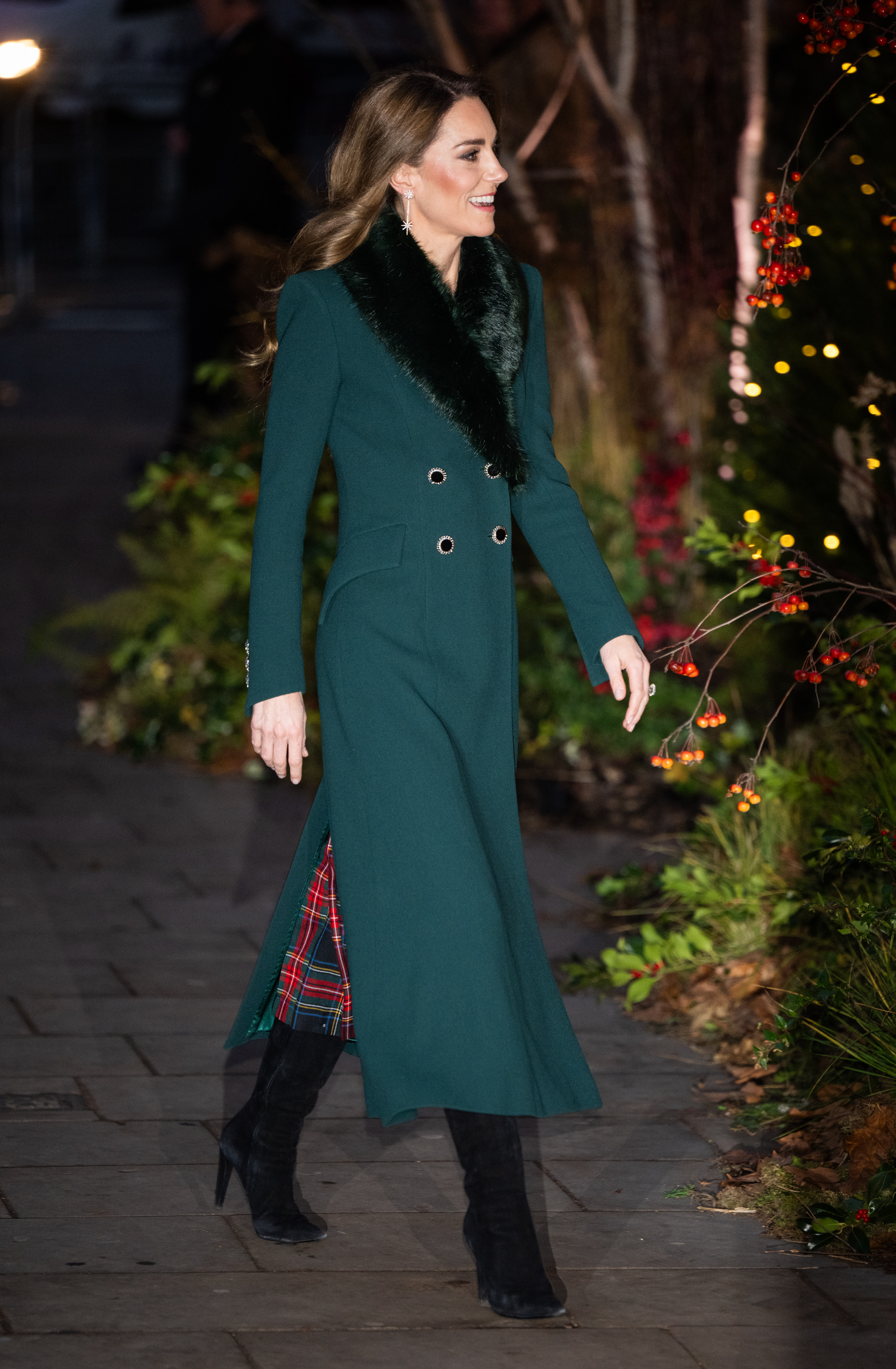 Kate Middleton wearing a green coat and walking past trees