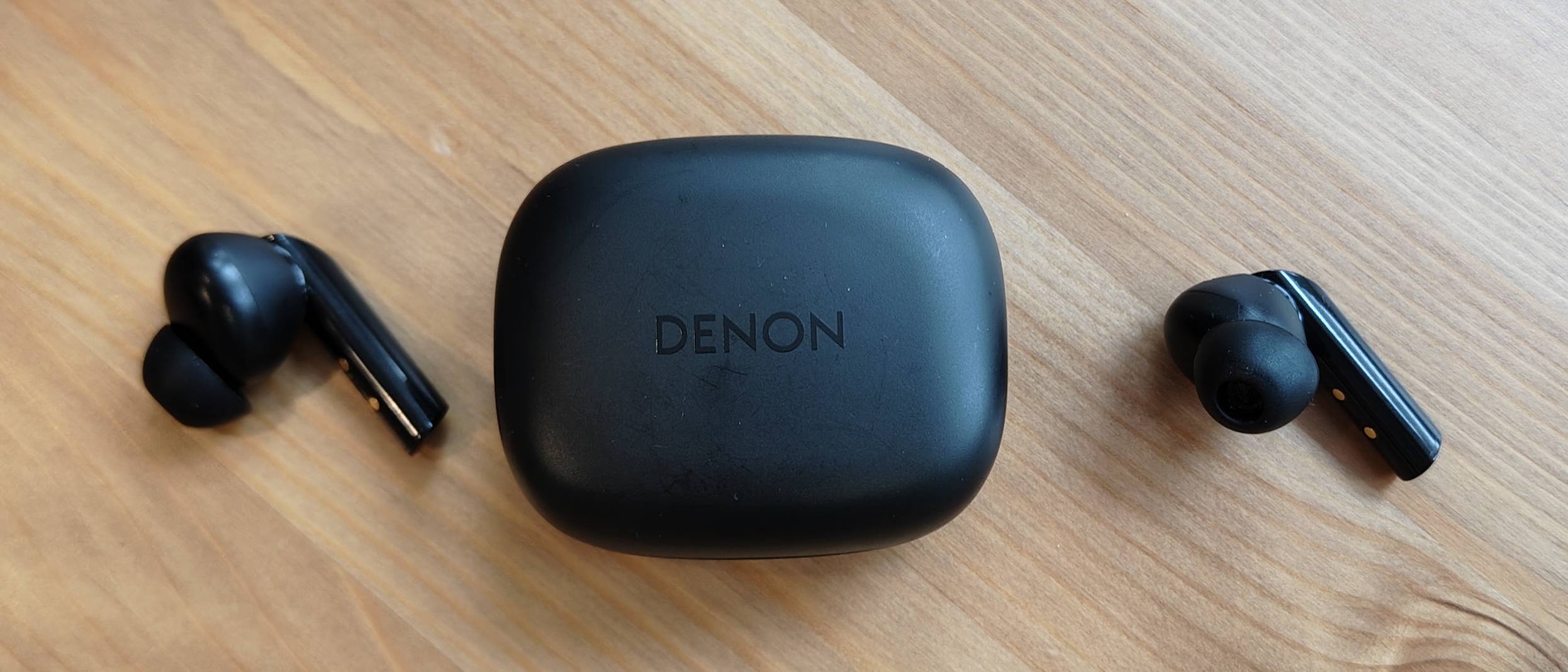 The Denon AH-C840NCW against a wooden table.