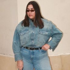 Gen Z Editor wearing denim shirt, denim jeans, black belt, and sunglasses standing on Parisian street.