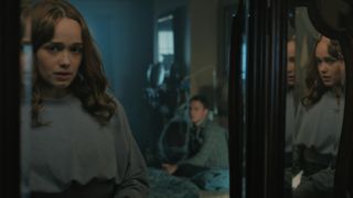 Lina (Rose Williams) looks into a mirror with Jamie (Finn Cole) sitting on the bed behind her, seen in the reflection
