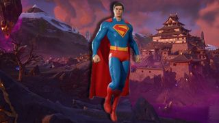 Superman hovers above a purple and red misted Japanese castle courtyard. Snowy mountains can be seen in the background