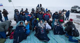 Surrounded by members of the search-and-rescue teams, NASA astronaut Joe Acaba (left), Russian cosmonaut Alexander Misurkin (center) and NASA astronaut Mark Vande Hei sit in reclining chairs outside the Soyuz MS-06 space capsule after their landing on Feb. 27, 2018.