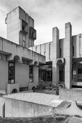 A black & white photo of a Nuffield Transplantation Surgery Unit. A modernist concrete building with protruding columns, concrete layers, and circular motifs.