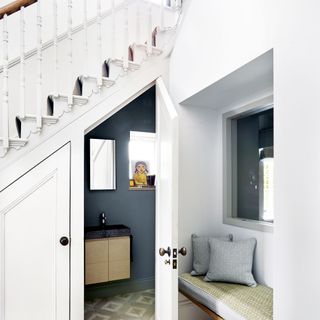 white hallway with navy blue downstairs toilet under the stairs