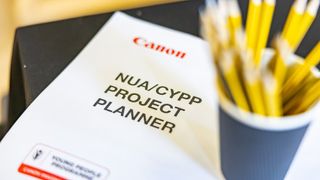 A close-up of a NUA/CYPP Project Planner with a cup of yellow pencils placed on top of it