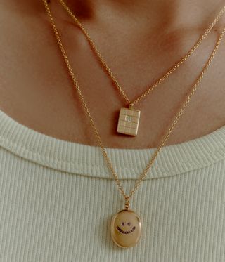 gold smiley face pendant and rectangular grid pendant around neck