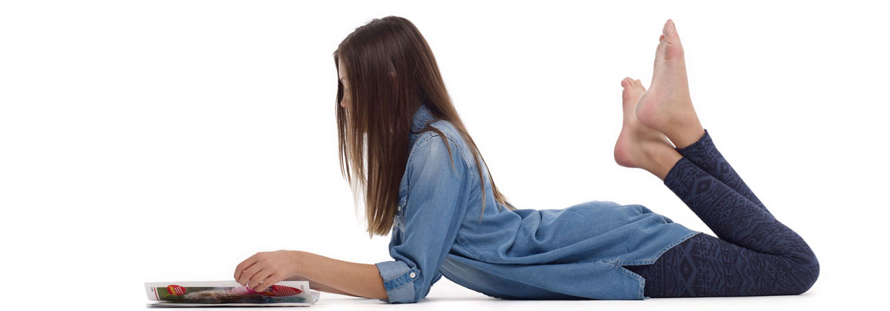 Girl laying on stomach reading magazine