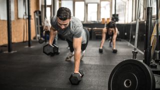 Man performs renegade row dumbbell exercise